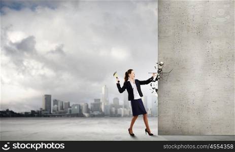 Woman with hammer. Young businesswoman hitting nail in wall with hammer