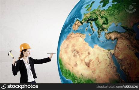 Woman with hammer. Young businesswoman with hammer hitting nail in Earth planet. Elements of this image are furnished by NASA