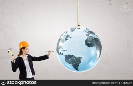 Woman with hammer. Young businesswoman with hammer hitting nail in Earth planet