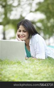 Woman with hand on chin looking at laptop screen and smiling