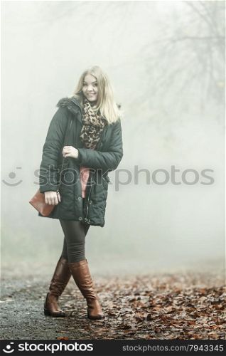 Woman with handbag walking relaxing in foggy day in romantic autumn forest park outdoor, tinted aged photo