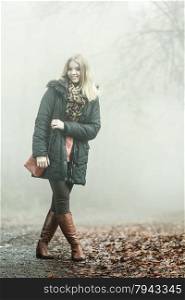 Woman with handbag walking relaxing in foggy day in romantic autumn forest park outdoor, tinted aged photo