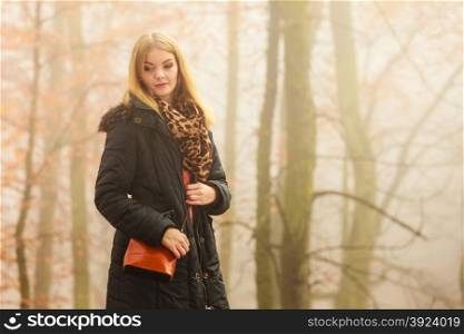 Woman with handbag walking relaxing in foggy day in romantic autumn forest park outdoor