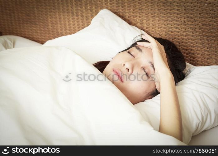 woman with headache lying on bed