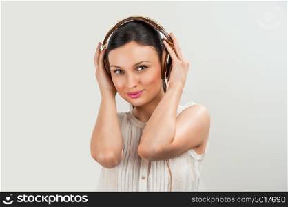 Woman with headphones listening music. Music teenager girl dancing against gray
