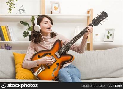 woman with headphones playing guitar