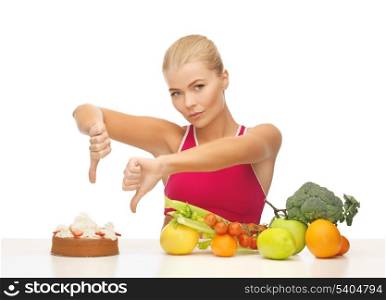 woman with healthy food showing thumbs down to cake