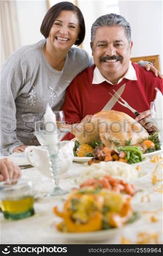 Woman With Her Arm Around Her Husband,Who Is Getting Ready To Carve A Turkey