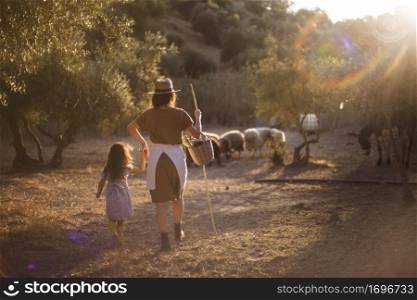 woman with her daughter herding sheep field