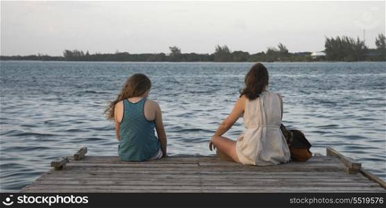 Woman with her daughter sitting on a pier, Utila Island, Bay Islands, Honduras