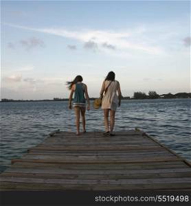 Woman with her daughter standing on a pier and looking at sea, Utila Island, Bay Islands, Honduras