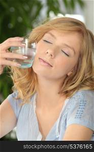 Woman with her eyes closed holding a glass of water
