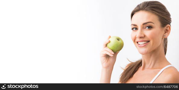 Woman with holding green apple. Beautiful smile, white strong teeth. Head and shoulders of young woman with snow-white toothy smile holding green apple, teethcare.