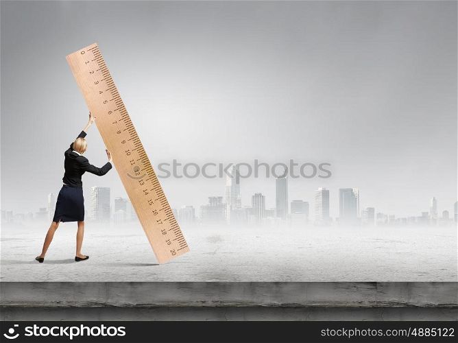 Woman with huge ruler. Young businesswoman measuring something with big ruler