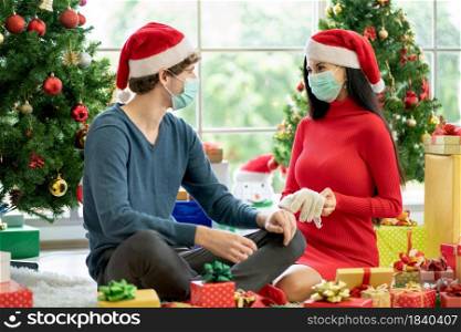 Woman with hygiene mask show gloves as the present to her lover with costume of Christmas festival during pandemic of Covid-19.