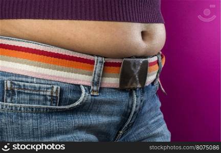 Woman with jeans shows her belly. Overweight.