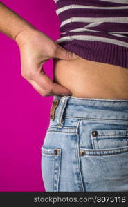 Woman with jeans shows her belly. Overweight.