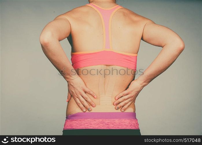 Woman with kinesiotaping application for back pain. Backache alternative kinesio tape therapy method. Health and body care.. Woman with medical kinesio taping on back
