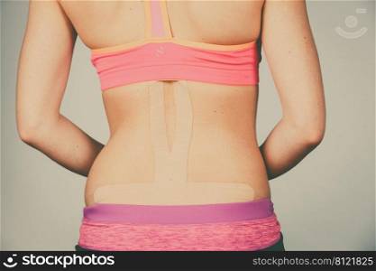 Woman with kinesiotaping application for back pain. Backache alternative kinesio tape therapy method. Health and body care.. Woman with medical kinesio taping on back