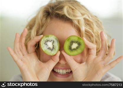 woman with kiwi slices in front of her eyes