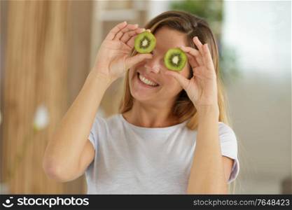 woman with kiwi slices in front of her eyes
