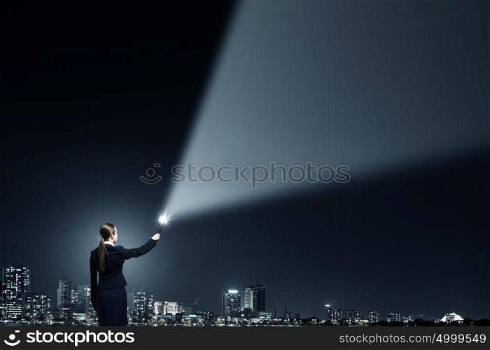 Woman with lantern in hand. Businesswoman in darkness with flashlight in hand