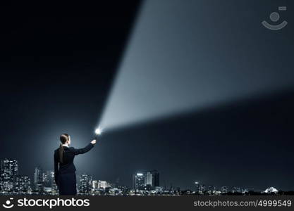 Woman with lantern in hand. Businesswoman in darkness with flashlight in hand