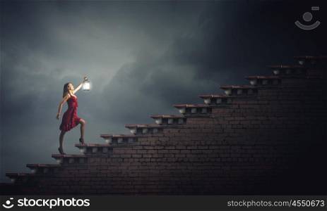Woman with lantern. Young girl in red dress walking on stair case