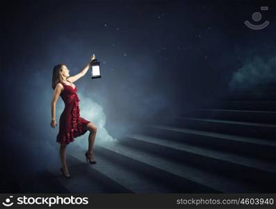 Woman with lantern. Young girl in red dress walking on stair case