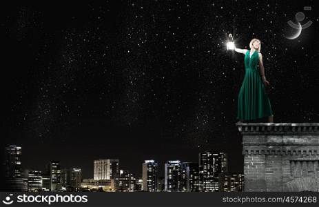 Woman with lantern. Young woman in green dress with lantern at night