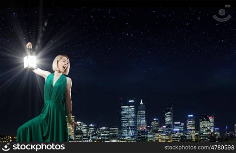Woman with lantern. Young woman in green dress with lantern at night