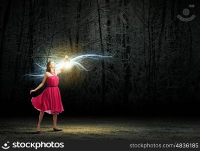 Woman with lantern. Young woman in red dress walking in night wood