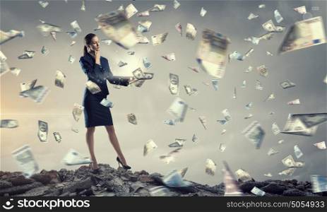 Woman with laptop in hands. Attractive thoughtful businesswoman with laptop in hands and money falling from sky