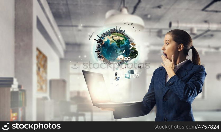 Woman with laptop in hands mixed media. Attractive shocked businesswoman with laptop in hands in modern office interior. Elements of this image are furnished by NASA