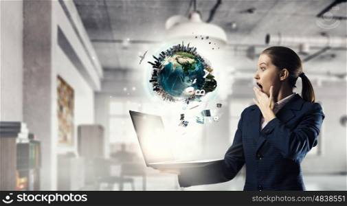 Woman with laptop in hands mixed media. Attractive shocked businesswoman with laptop in hands in modern office interior. Elements of this image are furnished by NASA