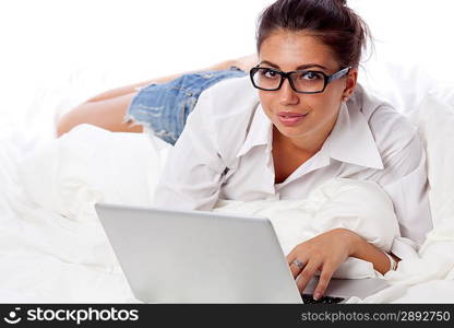 Woman with laptop lying in bed