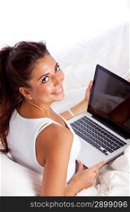 Woman with laptop lying in bed