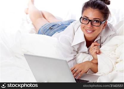 Woman with laptop lying in bed