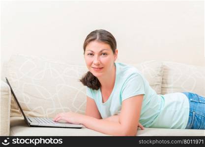 woman with laptop lying on the couch comfortably