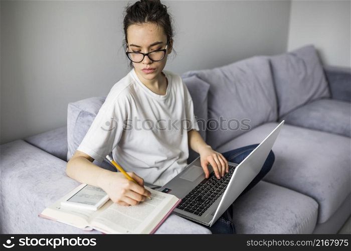 woman with laptop making notes book
