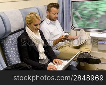 Woman with laptop man newspaper in train texting commuting reading