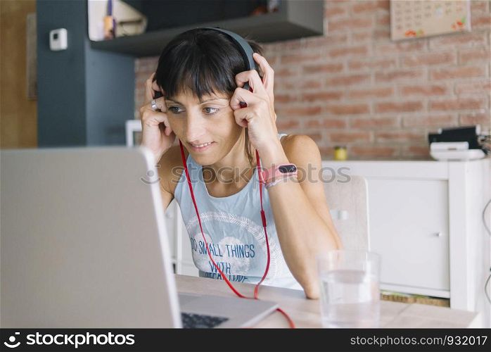 Woman with laptop working at home while listening music by headphones. Marta Rodriguez.jpg