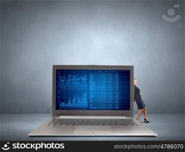 Woman with laptop. Young pretty businesswoman trying to move big laptop