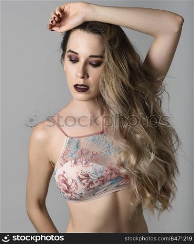 Woman with long hair and blue eyes wearing colored lingerie. Beautiful caucasian woman with very long hair and blue eyes. Female wearing colored lingerie. Wavy hairstyle. Studio shot.