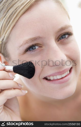 Woman with makeup brush smiling