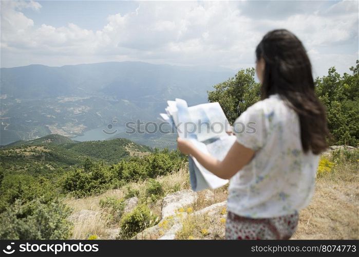 Woman with map high in the mountain. View