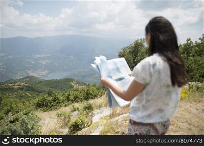 Woman with map high in the mountain. View