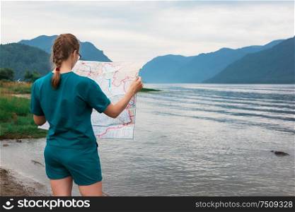 Woman with map on Teletskoye lake in Altai mountains, Siberia, Russia.. Teletskoye lake in Altai mountains