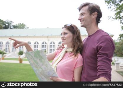Woman with map showing something to man against building