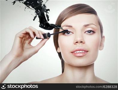 woman with mascara brush and black splash
